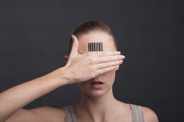 Studio portrait of woman with bar code on forehead