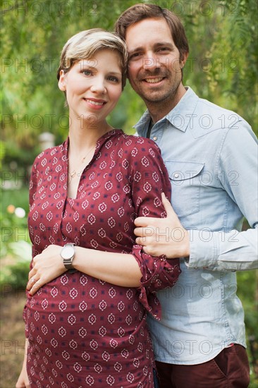 Pregnant couple embracing in garden