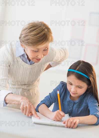 Teacher helping schoolgirl (8-9) at school.