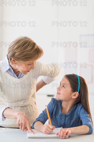 Teacher helping schoolgirl (8-9) at school.