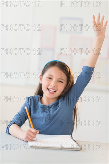 Portrait of schoolgirl (8-9) raising hand.