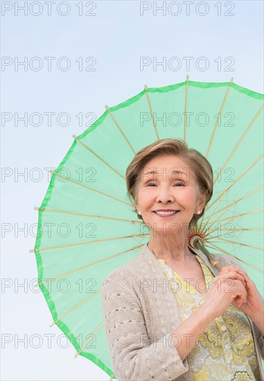 Portrait of senior woman holding green parasol.