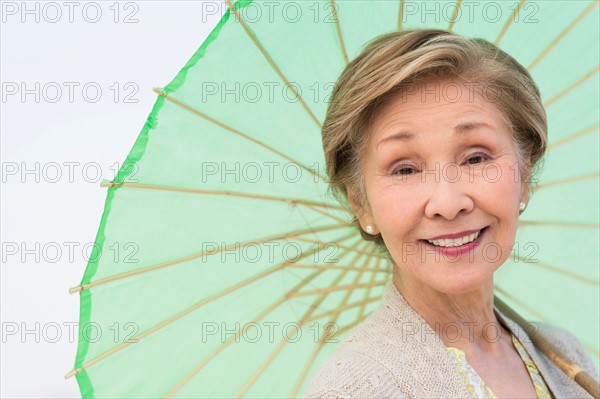 Portrait of senior woman holding green parasol.