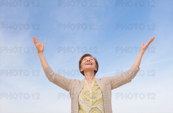 Senior woman looking up at blue sky.