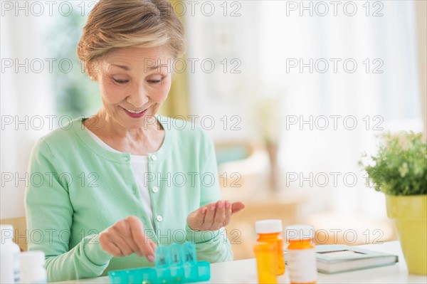 Senior woman organizing medicine in box.