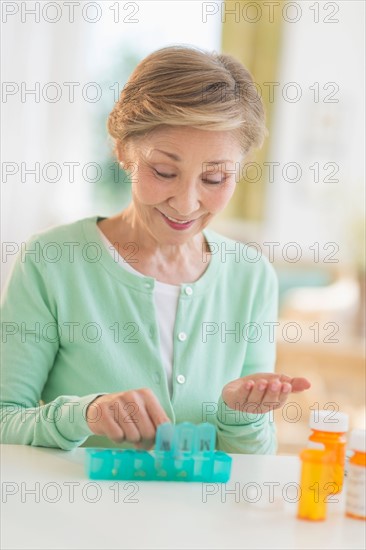 Senior woman organizing medicine in box.