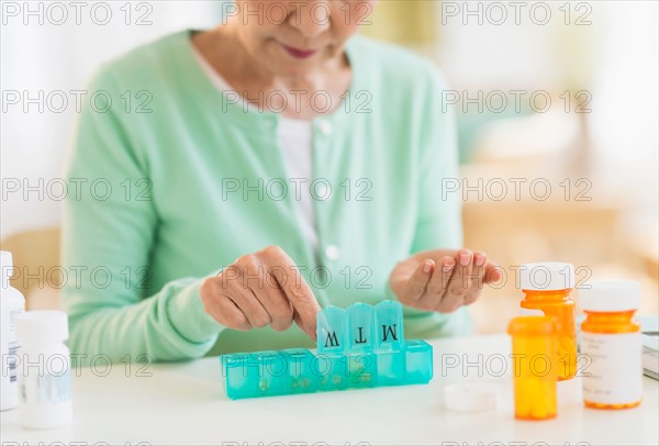Senior woman organizing medicine in box.