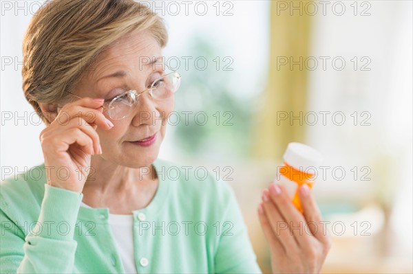 Senior woman reading medicine label.