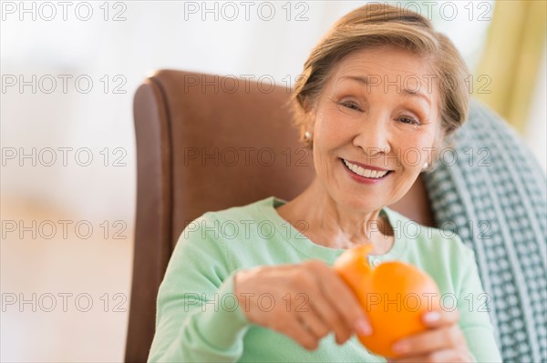 Portrait of senior woman peeling orange.