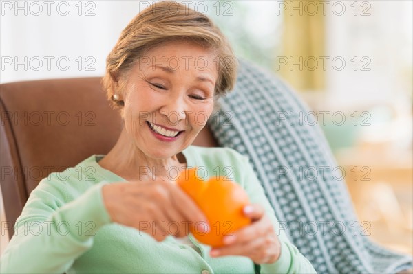 Portrait of senior woman peeling orange.