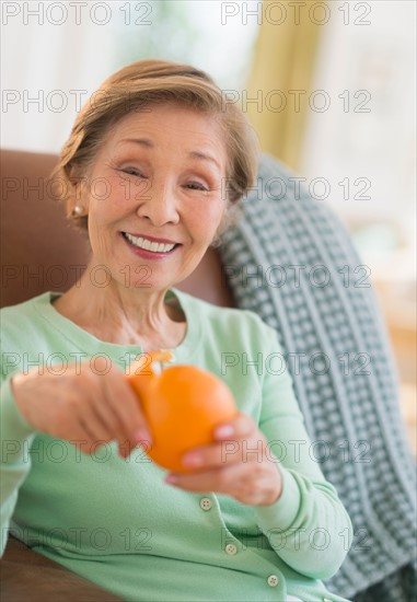 Portrait of senior woman peeling orange.