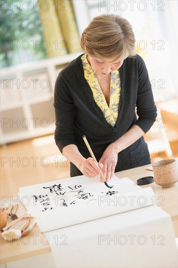 Senior woman painting japanese symbols.