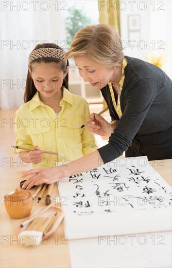 Grandmother and granddaughter (8-9) painting japanese symbols.