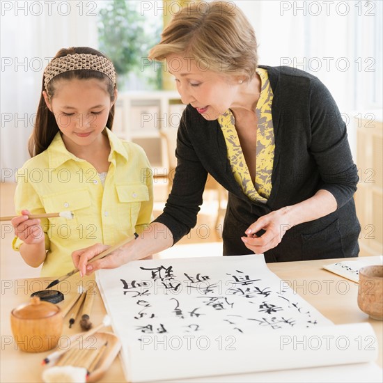Grandmother and granddaughter (8-9) painting japanese symbols.