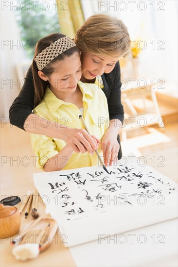 Grandmother and granddaughter (8-9) painting japanese symbols.