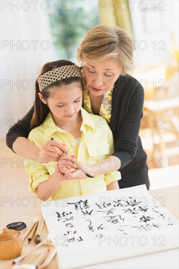 Grandmother and granddaughter (8-9) painting japanese symbols.