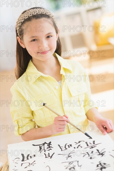 Portrait of girl (8-9) painting japanese symbols.