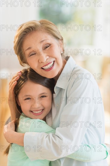 Grandmother embracing granddaughter (8-9).