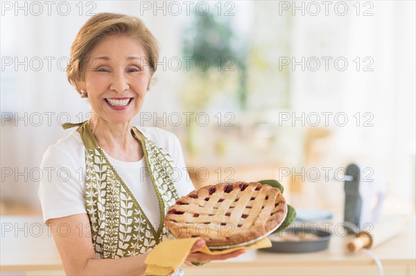 Senior woman holding freshly baked cake.