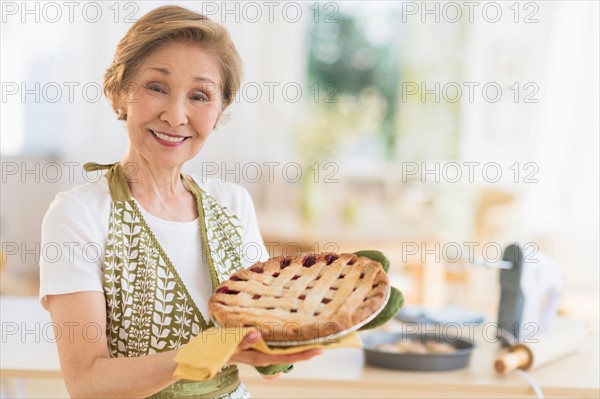Senior woman holding freshly baked cake.