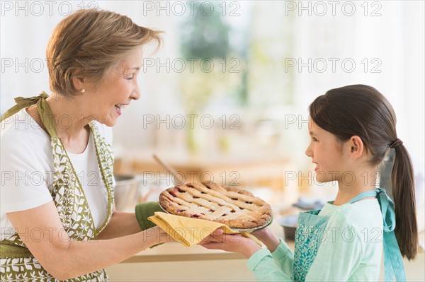 Grandmother and granddaughter (8-9) holding freshly baked pie.