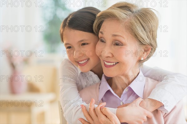 Granddaughter (8-9) embracing grandmother.