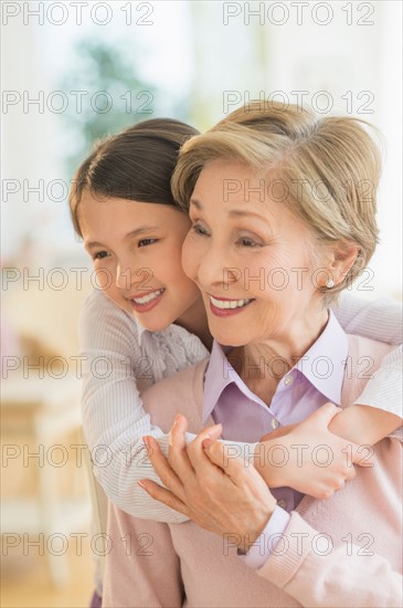 Granddaughter (8-9) embracing grandmother.