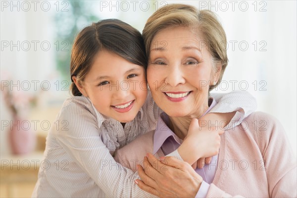 Granddaughter (8-9) embracing grandmother.