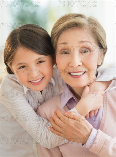 Granddaughter (8-9) embracing grandmother.