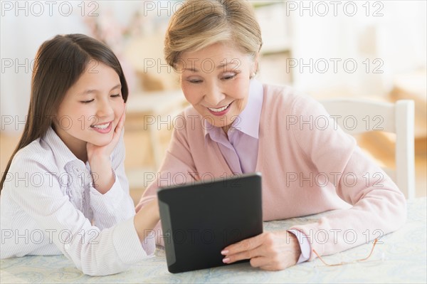Granddaughter (8-9) and grandmother using digital tablet.