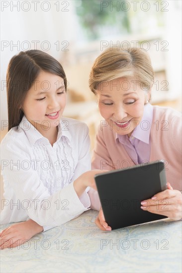 Granddaughter (8-9) and grandmother using digital tablet.