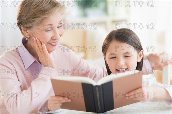 Granddaughter (8-9) and grandmother reading book.