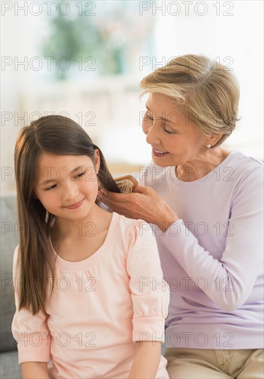 Grandmother brushing granddaughter's (8-9) hair.