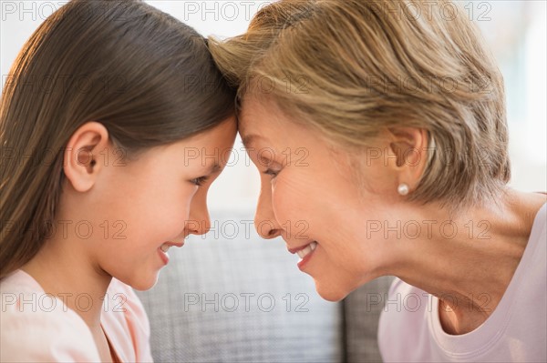 Granddaughter (8-9) and grandmother touching with heads.