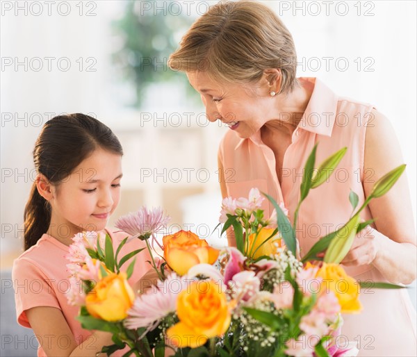 Granddaughter (8-9) and grandmother arranging flowers at home.