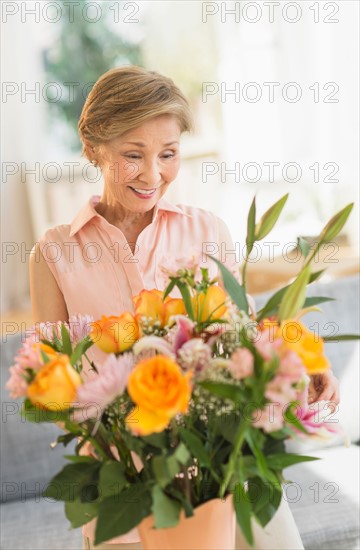 Senior woman arranging flowers at home.