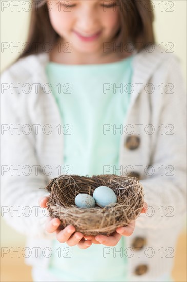 Girl (8-9) holding bird's nest with eggs.