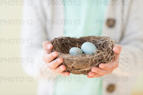 Girl (8-9) holding bird's nest with eggs.