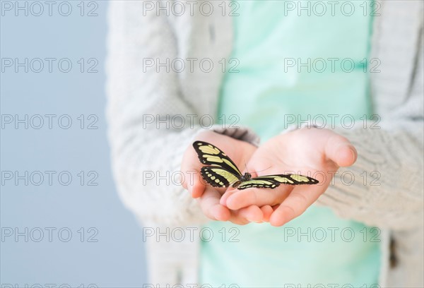 Girl (8-9) holding butterfly.