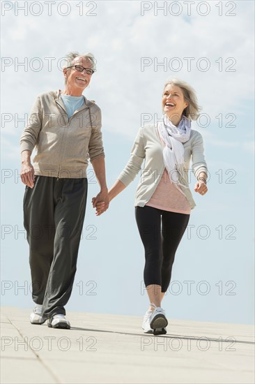 Senior couple walking and holding hands.