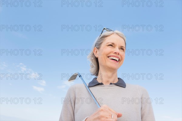 Senior woman holding golf club.