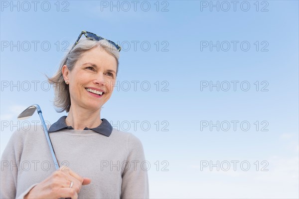 Senior woman holding golf club.