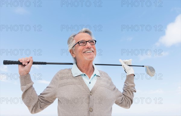 Senior man holding golf club.