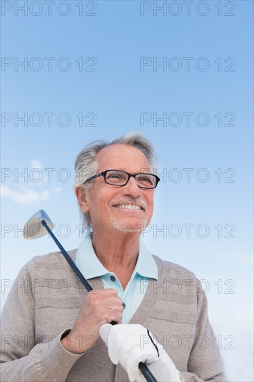 Senior man holding golf club.