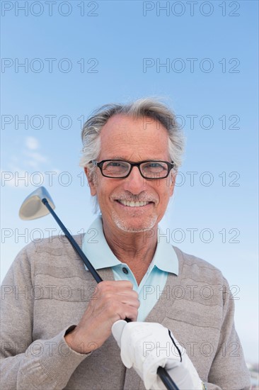 Senior man holding golf club.