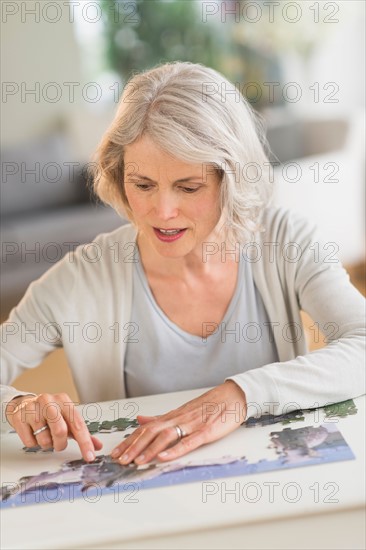 Senior woman completing jigsaw puzzle.