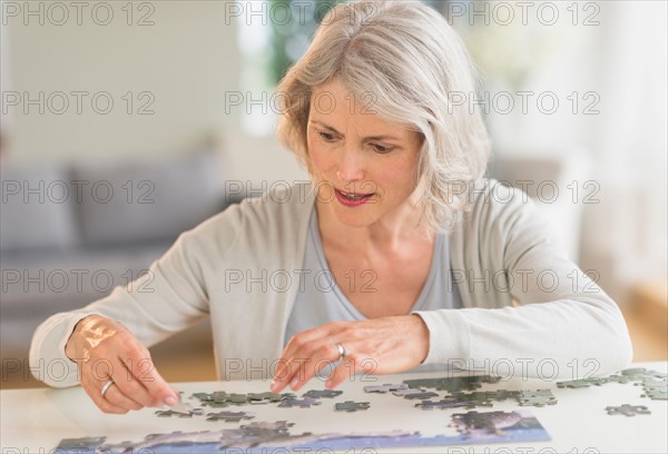 Senior woman completing jigsaw puzzle.