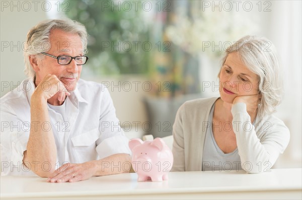 Senior couple looking at piggybank.