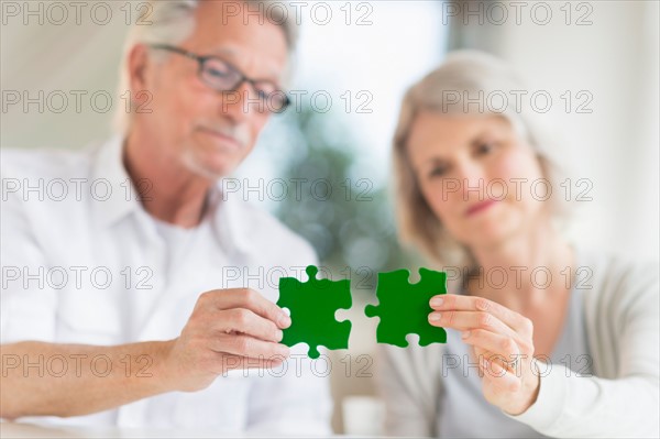 Senior couple holding matching jigsaw pieces.