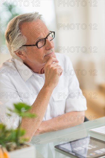 Portrait of senior man thinking at desk.